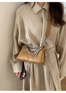 Dettaglio della borsa a mezzaluna in pelle cammello con catena d'argento sul modello