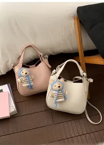 Detail of lychee textured bucket bags in pink and beige with cute knitted bear charms