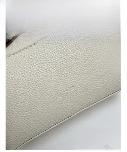 Detail of white lychee grain leather handbag with NO FILTER embossed text and stitching