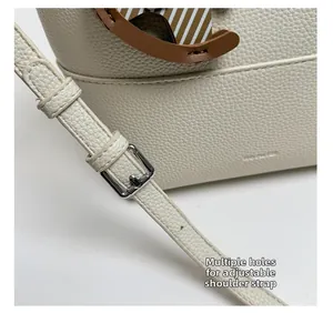 Detail of adjustable shoulder strap with metal buckle on beige lychee leather bag