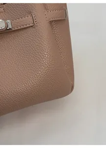 Vue détaillée de la texture du cuir grainé et du fermoir en métal argenté poli du sac
