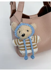 Charming plush bear charm with blue hat on a stylish pink leather bucket bag