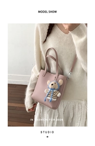 Close-up of pink litchi grain tote bag with a cute plush bear charm for casual styling