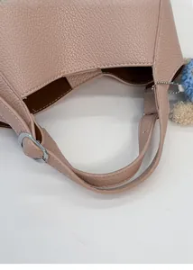 Close-up of pink litchi grain leather bucket bag with silver buckle and plush charm