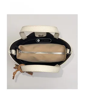 Detail view of cream bucket bag showing lychee grain leather and interior zip pouch