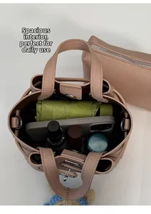 Intérieur spacieux du sac seau rose poudré contenant téléphone, parapluie et cosmétiques