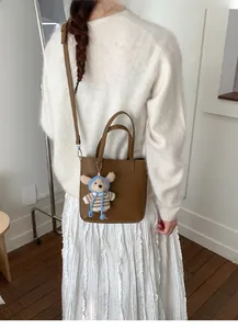 Detail of brown lychee grain leather bucket bag with a cute knitted bear charm accessory