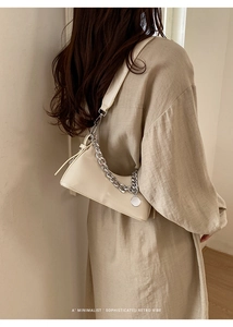 Dettaglio di una borsa a mezzaluna beige con catena in metallo argento e tracolla