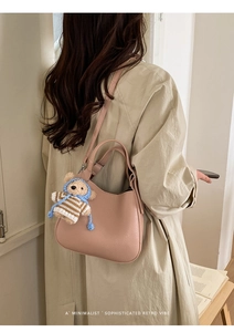 Detail of pink bucket bag with lychee texture and cute teddy bear plush charm
