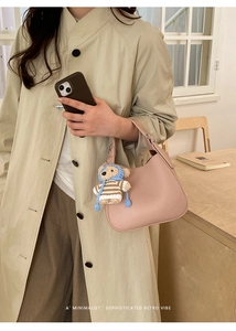 Detail of light pink pebbled leather shoulder bag with a cute knitted bear accessory