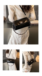Details einer glänzenden schwarzen Umhängetasche mit silbernem Drehverschluss und Kette