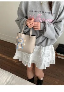 Detail of beige lychee texture bucket bag with cute bear pendant for daily commute