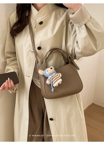 Detail of dark brown lychee texture bucket bag with a cute teddy bear plush charm