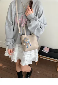 Beige bucket tote bag with cute bear charm and adjustable strap for street style