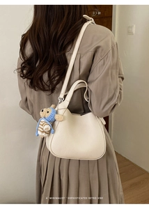 Close-up of off-white lychee pattern bucket bag with cute bear charm on model