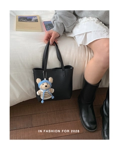 Detail view of black lychee grain tote bag featuring a cute bear keychain and top handles
