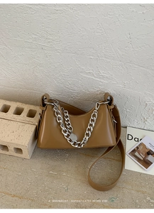 Dettaglio di una borsa a spalla in pelle color cammello con catena d'argento decorativa