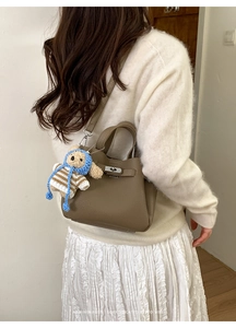 Sac seau en cuir marron avec fermoir argenté et breloque ours porté par un mannequin