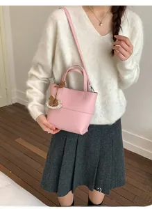 Pink lychee grain leather bucket bag with wooden horse charm shown in lifestyle setting