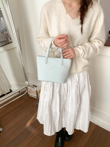 Detail of light blue textured leather tote bag with elegant thin handles for women