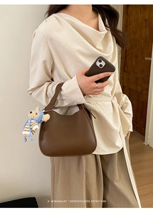 Detail showing deep brown lychee texture bucket bag with a cute bear knit pendant charm