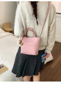 Close-up of pink litchi grain leather bucket bag with shoulder strap and charm