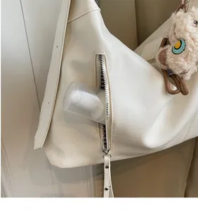 Détail de la poche zippée latérale d'un sac cabas en cuir beige avec charme peluche