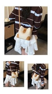 Detail view of cream and brown bucket bag showing golden twist lock and lychee texture
