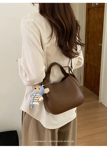 Brown bucket bag side view featuring a cute teddy bear pendant on a minimalist retro strap