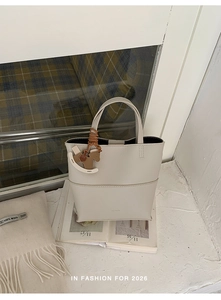 Détail du sac seau beige en cuir grainé avec un pendentif cheval en bois décoratif