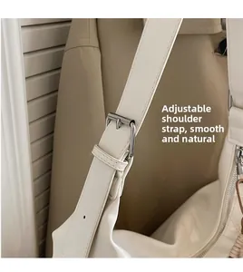 Détail de la bandoulière réglable avec boucle en métal argenté sur un sac à main blanc