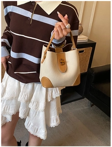 Close-up of a cream and caramel bucket bag with a vintage gold twist-lock closure