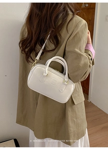 Chic beige crossbody bag with gold hardware and removable strap on model in suit