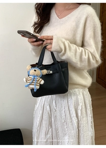 Détail du sac seau noir en cuir grainé avec fermoir classique et breloque ours