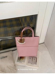 Détail d'un sac cabas rose grainé avec pendentif cheval et écharpe en laine blanche
