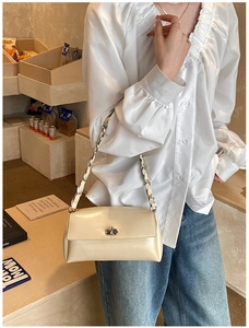 Detail der cremefarbenen Lackleder-Baguette-Tasche mit silberner Kette am Model