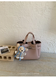 Détail du sac seau en cuir grainé rose poudré avec breloque ours et fermoir argenté