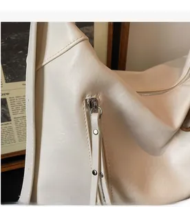 Détail du zip argenté et des tirettes longues en similicuir sur un sac crème