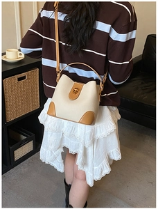 Detail of vintage beige and brown bucket bag with golden buckle on a shoulder strap