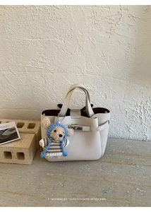 Détail d'un sac à main en cuir grainé blanc cassé avec pendentif ours et boucle argentée