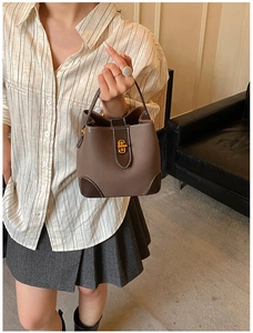 Detail of dark brown leather bucket bag with gold clasp and white stitching accent