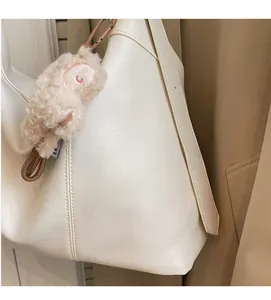 Gros plan détaillé du sac à bandoulière blanc crème avec texture souple et breloque ours