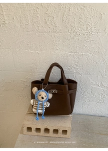 Détail du sac en cuir marron foncé avec fermoir rétro et breloque ours mignonne
