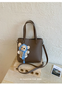 Close-up of dark brown lychee texture leather bucket bag with a cute bear charm