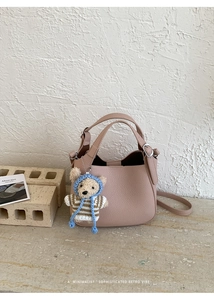 Close-up of pink bucket bag with lychee texture leather and teddy bear charm