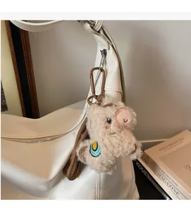 Détail d'un charme de sac cochon en laine d'agneau sur un sac à main en cuir blanc