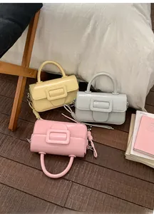 Borse quadrate minimaliste in colori macaron giallo, grigio e rosa su pavimento in legno