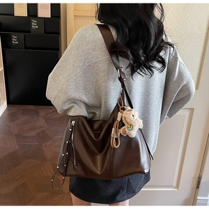 Détail du sac cabas marron vintage avec rivets métalliques et accessoire ours en peluche