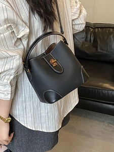 Classic black bucket bag with white contrast stitching and a gold turn-lock closure
