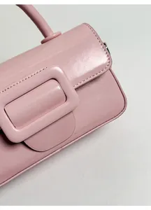 Primo piano della borsa in pelle rosa con texture opaca e grande fibbia quadrata